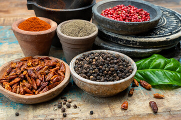 Colorful ground spicy chili peppers , pimento and curcuma is clay pots close up