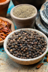 Indian spices collection, dried black peppercorns and another spices in clay bowls