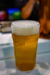 Fresh draught lager or IPA beer is glass served in indoor cafe close up, pint of beer