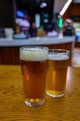 Fresh draught lager or IPA beer is glass served in indoor cafe close up, pint of beer
