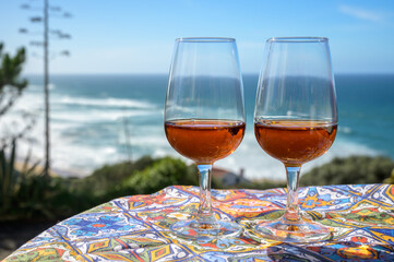 Tasting of sweet moscatel de setubal or porto portuguese wine and view on blue Atlantic ocean near...