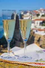 Glasses of champagne sparkling wine and view on white houses of picturesque village Azenhas do mar, Lisbon area, Portugal