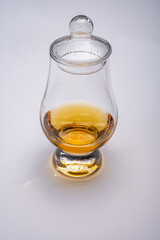 Tulip-shaped tasting glass with dram of Scotch single malt or blended whisky on white background