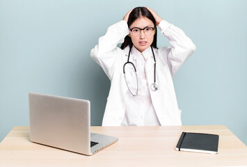 pretty asian woman feeling stressed, anxious or scared, with hands on head. physician desk and...