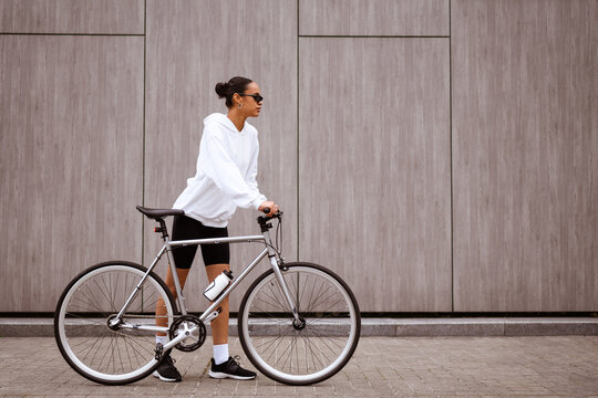 Stylish African American Woman In Sunglasses Walking Near Bicycle On Street 