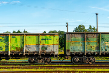 Fototapeta na wymiar Cargo transportation by rail. There is a transport train with containers on the railway track. Logistics, transportation of essential goods, grain, fuel, industrial goods.
