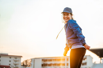 Portrait of Happy young asian woman stand on track race in the morning at sport stadium in the city.she wearing sportswear and cap.Jogging, fitness, running, exercise, lifestyle, healthy concept.