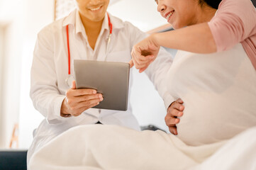 Obraz premium Male doctor hold patient have consultation tablets with pregnant woman in hospital. Female gynecologist talk consult female check pregnancy before giving birth. Maternity concept.