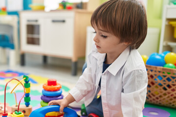 Adorable toddler playing toys sitting on floor at kindergarten