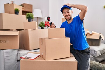 Hispanic man with beard working moving boxes stressed and frustrated with hand on head, surprised and angry face