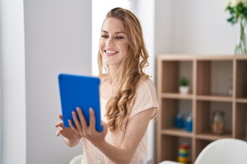 Young blonde woman smiling confident using touchpad at home