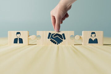 The hand holds wooden wooden blocks with icons of a woman and a man and shaking hands in the act of consent. The concept of divorce, agreement, mediation, the role of the mediator. - obrazy, fototapety, plakaty
