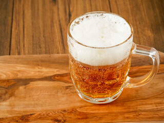 Massive beer mug with rich foam on a wooden table in a bar. Glass of fresh lager.