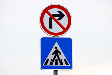 Blue and white pedestrian crossing sign on the sky background with prohibited from turning right.