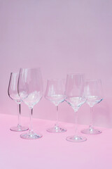 Various empty wine glasses on a pink background with space for text.