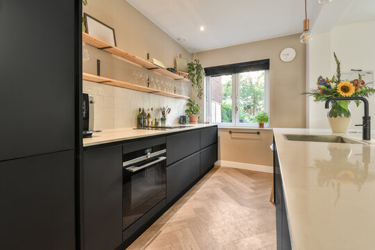a modern kitchen with black cabinets and white countertops in the center of the image is an open window that looks out onto the