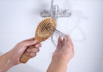 A woman suffering from alopecia is looking at hair caught on a comb while taking a shower