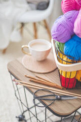 Cozy homely atmosphere. Female hobby knitting. Yarn pastel multicolor in a basket. Skeins, balls, knitting needles, hooks and scissors.