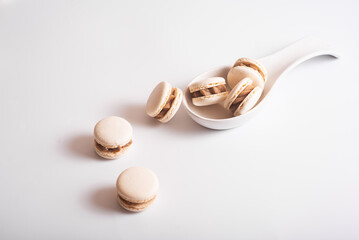 Tasty almond macarons in ceramic white spoon on white background. Copy space
