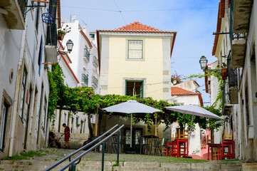 Lisbon, Portugal, November 6, 2022. Walking on narrow hilly streets of Alfama, old part of Lisbon city, white houses and many steps