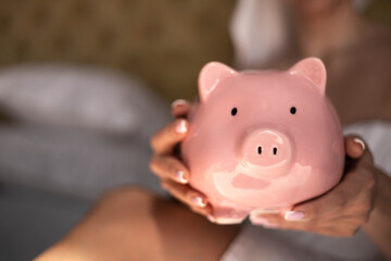 Closeup female hands holding pink piggy bank or money box with savings savings financial cash coins