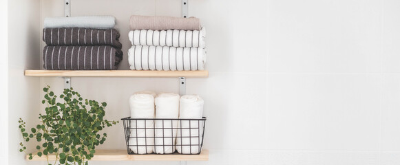 Towels roll neatly folded metallic basket arrangement wooden shelves minimal bathroom interior