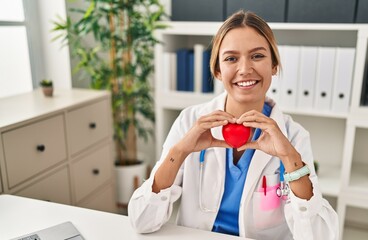 Young hispanic woman wearing doctor uniform wearing gloves at clinic