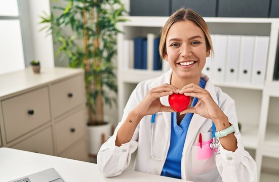 Young hispanic woman wearing doctor uniform wearing gloves at clinic