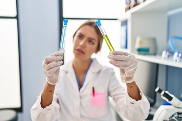 Young hispanic woman scientist holding test tubes at laboratory