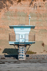San Diego, USA. September 20, 2022. Empty lifeguard tower on sandy beach with mountain in the background during sunny day