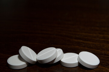 White round tablets on a wooden surface. A medicinal product.
