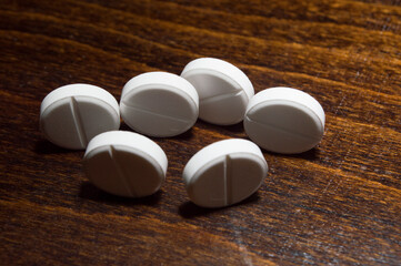 White round tablets on a wooden surface. A medicinal product.