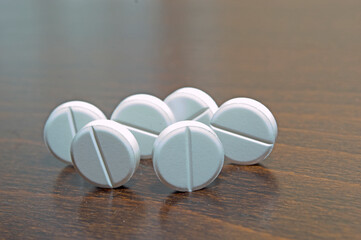 White round tablets on a wooden surface. A medicinal product.