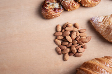 Closeup of almonds in wooden spoon with bread on wooden background, vintage tones, breadbread
