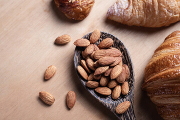 Closeup of almonds in wooden spoon with bread on wooden background, vintage tones, breadbread
