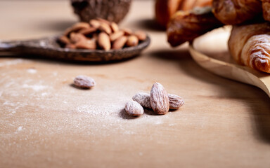 Closeup of almonds in wooden spoon with bread on wooden background, vintage tones, breadbread

