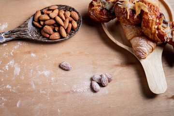 Closeup of almonds in wooden spoon with bread on wooden background, vintage tones, breadbread
