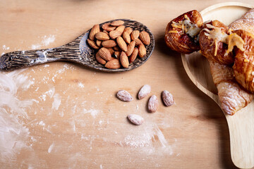 Closeup of almonds in wooden spoon with bread on wooden background, vintage tones, breadbread
