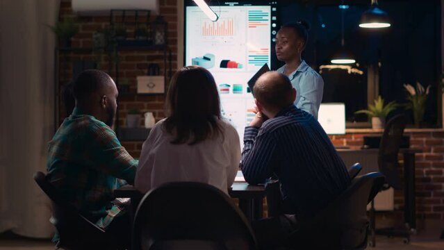 African american employee presenting report, showing charts on laptop screen. Company research statistics presentation, diverse team discussing analytics, planning sales strategy