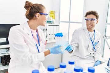 Fototapeta premium Man and woman wearing scientist uniform holding test tube at laboratory
