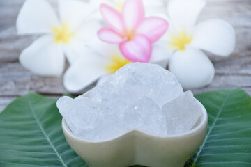 Alum cubes on ceramic pot and plumeria flowers background, concept for herb, bodycare, skincare, waterclear, spa, treatment, disease protection and protect armpit smell.	