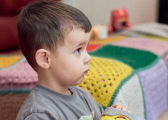 Fototapeta na wymiar Expressive boy watching cartoons in the livingroom