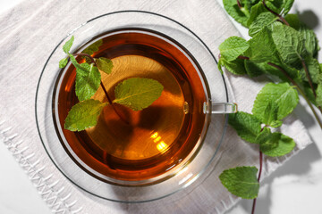Cup of aromatic herbal tea with mint on white table, top view