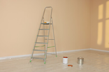 Metal stepladder near pale orange wall indoors. Room renovation