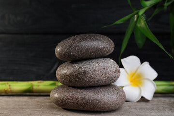 Stacked spa stones, bamboo and flower on wooden table