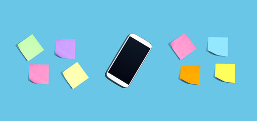 Smartphone with many colorful sticky notes - desk flat lay