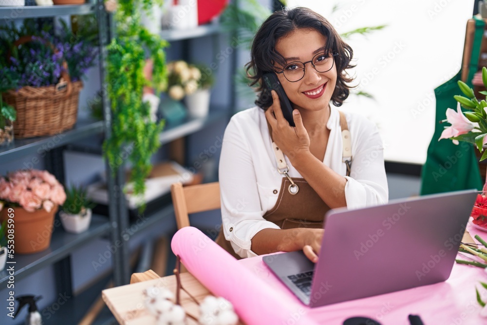 Canvas Prints young beautiful hispanic woman florist talking on smartphone using laptop at flower shop