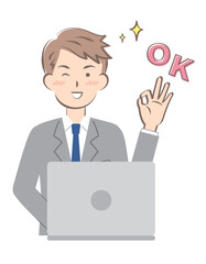パソコン操作でOKサインを出すスーツ姿の若い男性
