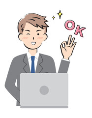 パソコン操作でOKサインを出すスーツ姿の若い男性