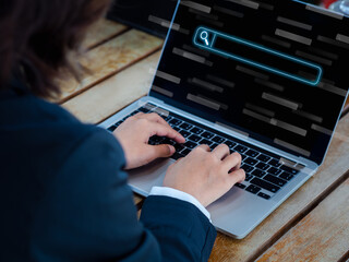 Search engine bar on laptop screen and businesswoman's hand using notebook computer on desk. Data...